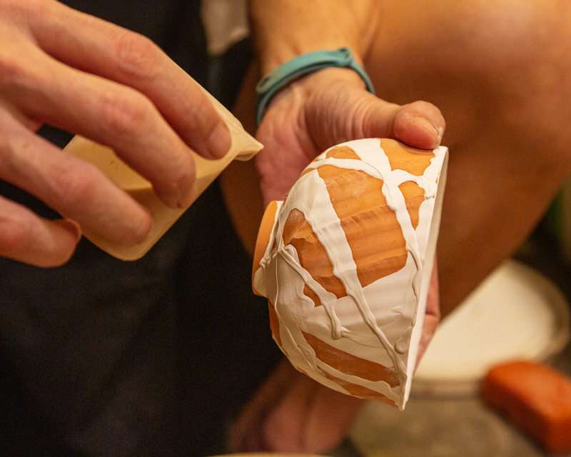 Glazing a ceramic cup before firing. Jimmywoh carefully applying glaze to a ceramic cup, preparing it for the final firing process.