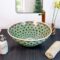 Luxurious ceramic sink adorned with detailed peacock feather patterns in rich blue and gold hues.