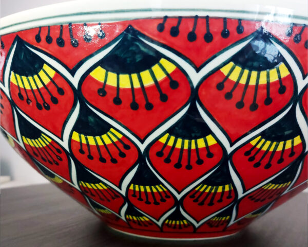 Side view of a red and gold ceramic basin, showing the depth and intricate lotus pattern.