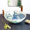 Thai-inspired ceramic sink featuring a majestic blue peacock design, showcasing exquisite craftsmanship.
