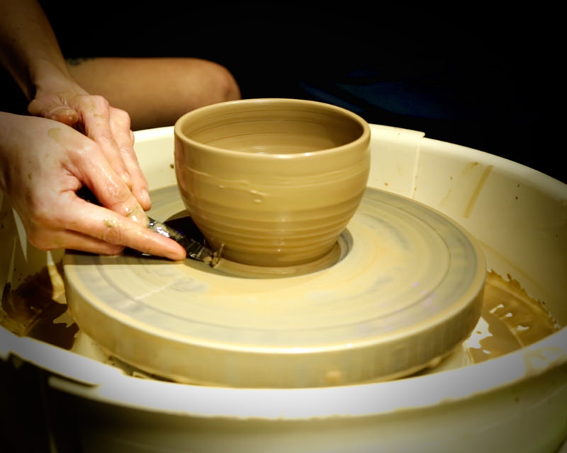 Shaping a ceramic cup on the potter’s wheel | Sabai Home A partially shaped ceramic cup spinning on a potter’s wheel, with the artisan’s hands carefully molding the clay