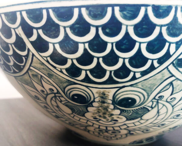 Side profile of the ceramic basin with hand painted Thai mythical figures and flourishes