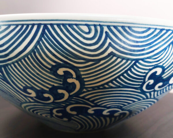 Side profile of Tidal Flow handmade ceramic basin, highlighting curvature and painted wave patterns.
